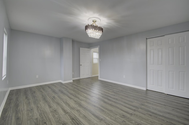 unfurnished bedroom featuring dark hardwood / wood-style floors, a closet, and a notable chandelier