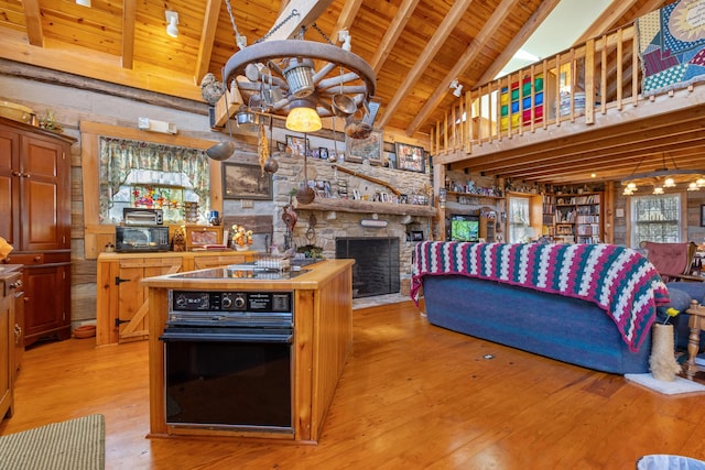 kitchen featuring butcher block countertops, a fireplace, wood ceiling, light wood-style floors, and black appliances