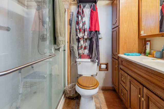 full bathroom featuring a stall shower, vanity, toilet, and baseboards