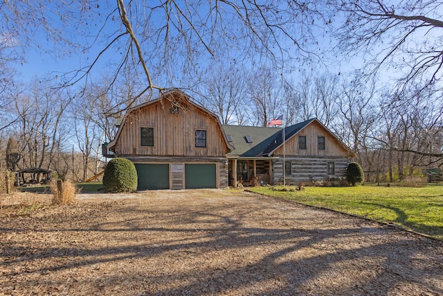 view of front of home featuring driveway, a barn, a garage, a gambrel roof, and a front lawn