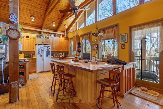 kitchen with butcher block countertops, beamed ceiling, light wood-style flooring, and freestanding refrigerator