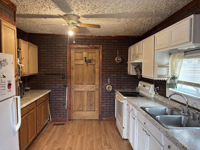 kitchen with white cabinetry, white appliances, sink, and brick wall