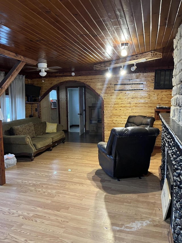 living room featuring light wood-type flooring, ceiling fan, wooden ceiling, and wood walls