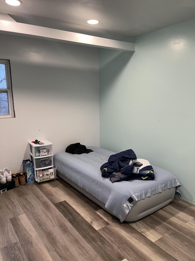 bedroom with beamed ceiling and hardwood / wood-style flooring