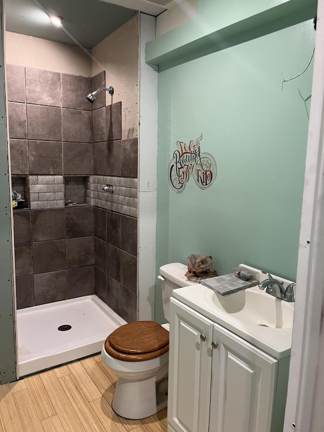 bathroom featuring vanity, toilet, and a tile shower