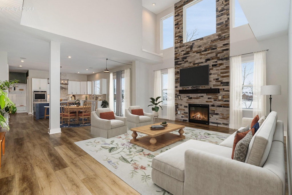 living room with a fireplace, a towering ceiling, and hardwood / wood-style floors