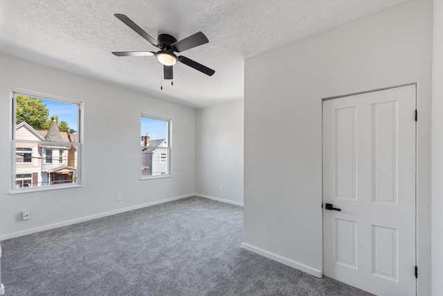 carpeted spare room featuring ceiling fan and a textured ceiling