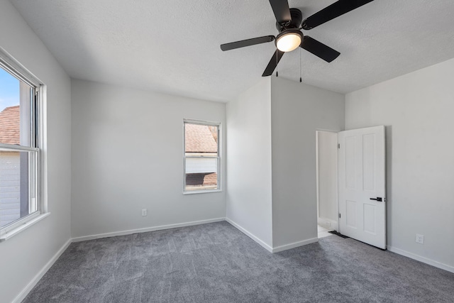 unfurnished room with ceiling fan, dark carpet, and a textured ceiling