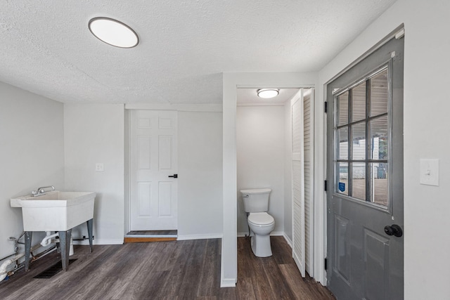 bathroom with wood-type flooring, a textured ceiling, and toilet