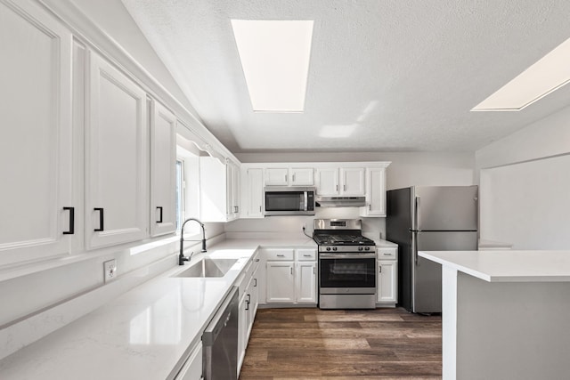 kitchen featuring white cabinetry, sink, appliances with stainless steel finishes, and a skylight