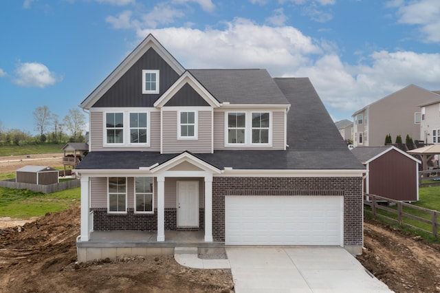 craftsman house with fence, brick siding, board and batten siding, covered porch, and driveway