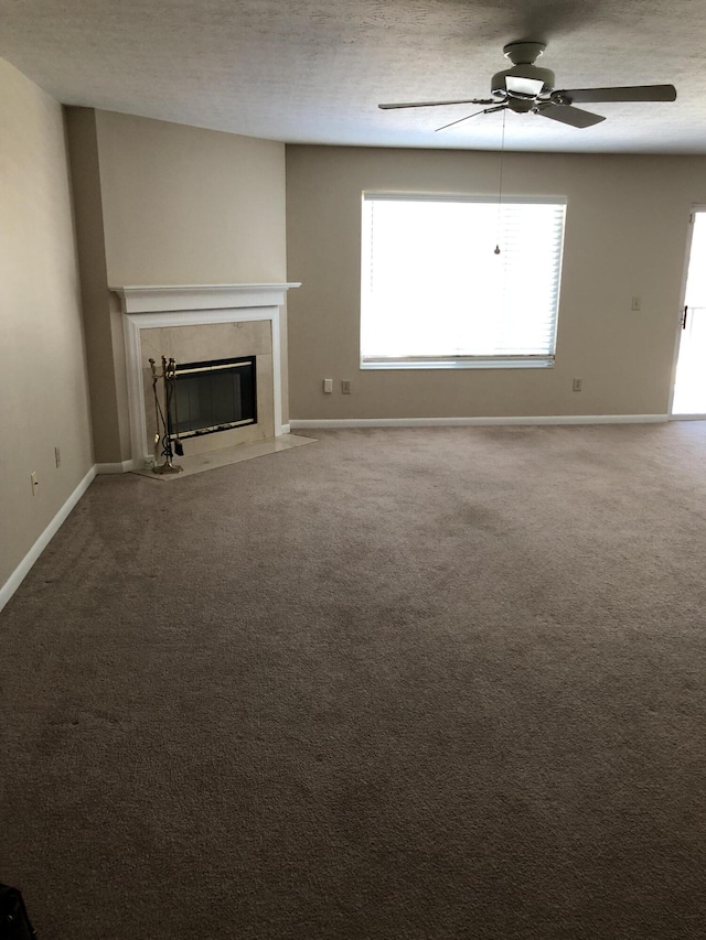 unfurnished living room featuring a textured ceiling, ceiling fan, a premium fireplace, and carpet floors