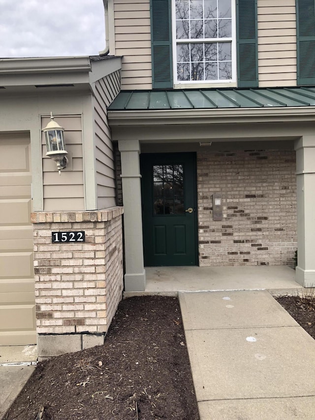 doorway to property with a standing seam roof, brick siding, and metal roof