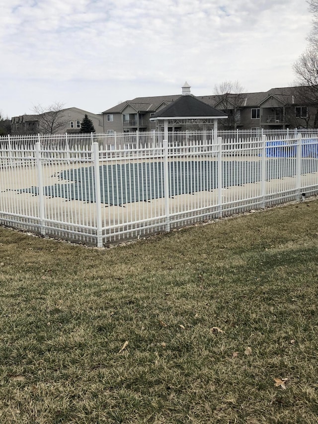 view of swimming pool with a yard, fence, and a swimming pool