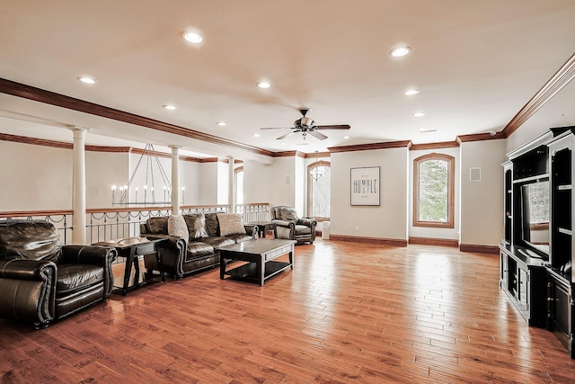 living room featuring ornate columns, crown molding, ceiling fan with notable chandelier, and hardwood / wood-style flooring