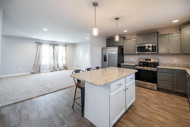 kitchen featuring a center island, hardwood / wood-style flooring, a kitchen breakfast bar, pendant lighting, and stainless steel appliances