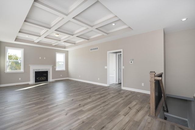 living room featuring beam ceiling, coffered ceiling, a premium fireplace, light hardwood / wood-style flooring, and crown molding