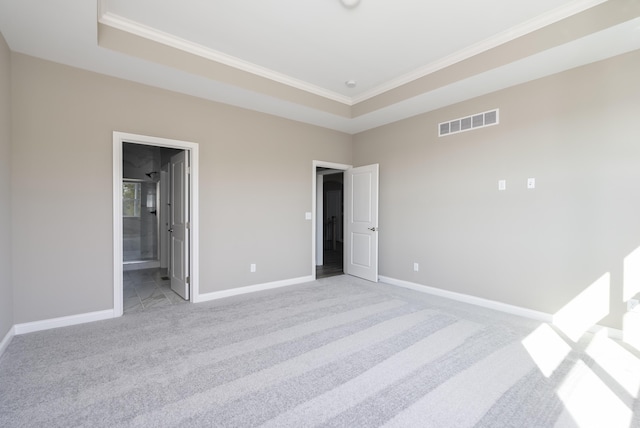 unfurnished bedroom featuring a raised ceiling, ensuite bathroom, light carpet, and ornamental molding