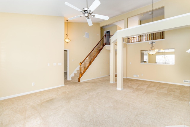 unfurnished living room featuring carpet flooring, ceiling fan, and a high ceiling