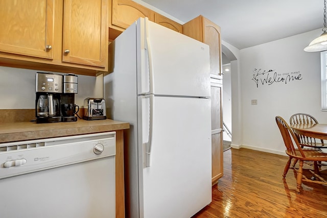 kitchen with light brown cabinetry, white appliances, light hardwood / wood-style floors, and hanging light fixtures