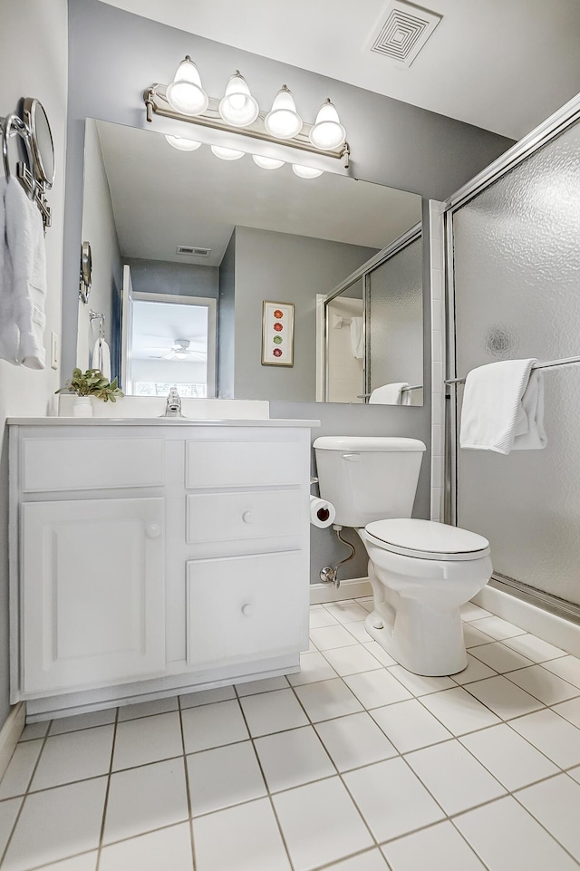 bathroom featuring tile patterned flooring, vanity, toilet, and a shower with shower door