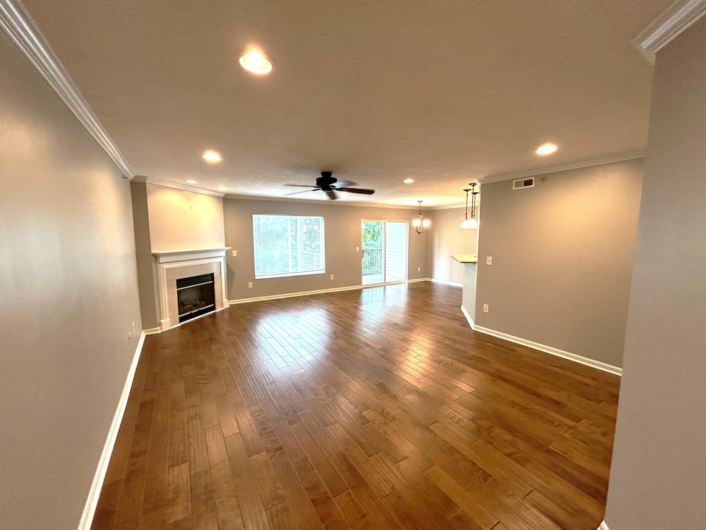 unfurnished living room featuring ceiling fan, dark hardwood / wood-style flooring, and ornamental molding