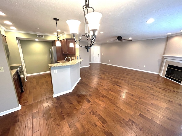 kitchen featuring ceiling fan with notable chandelier, a textured ceiling, a large fireplace, stainless steel appliances, and decorative light fixtures