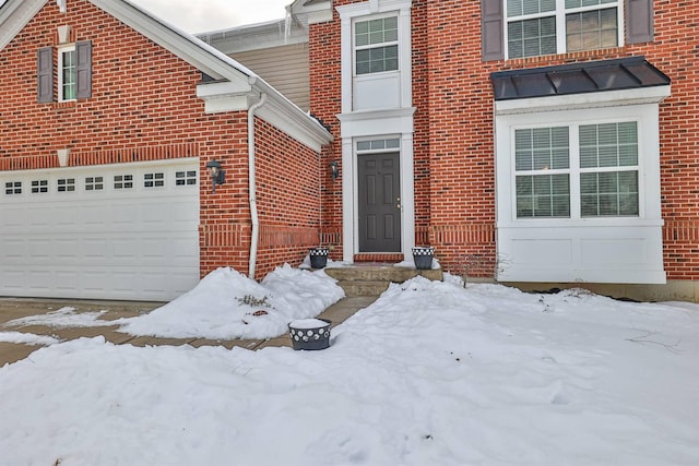 snow covered property entrance with a garage