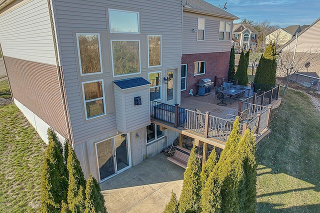 back of house with a deck, a lawn, and a patio