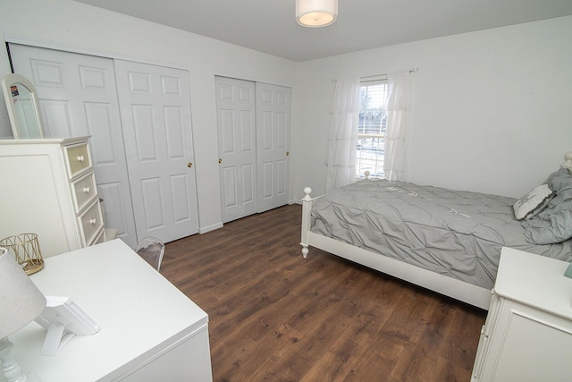 bedroom with dark wood-type flooring and two closets