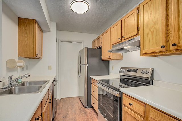 kitchen with a textured ceiling, stainless steel appliances, light hardwood / wood-style flooring, and sink