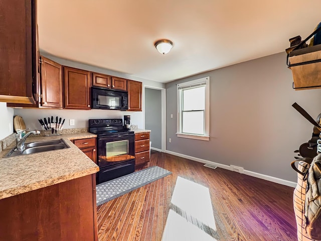 kitchen with sink, dark wood-type flooring, and black appliances