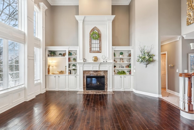 unfurnished living room with a towering ceiling, a premium fireplace, crown molding, and dark hardwood / wood-style floors