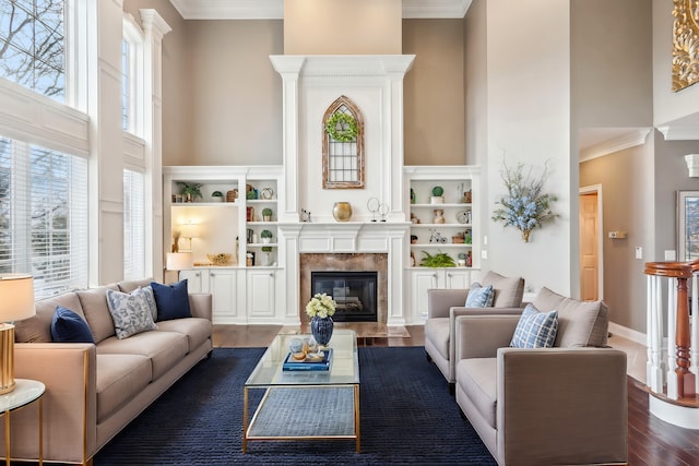 living room with dark wood-type flooring, a high end fireplace, a high ceiling, and ornamental molding