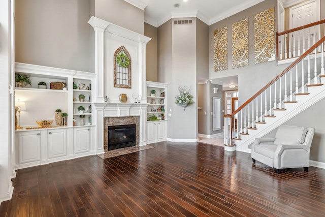 unfurnished living room with wood-type flooring, a wealth of natural light, crown molding, and a premium fireplace