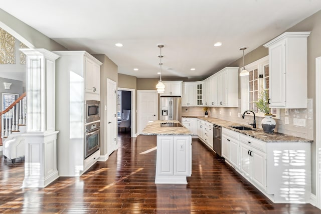 kitchen featuring stainless steel appliances, sink, hanging light fixtures, and a center island