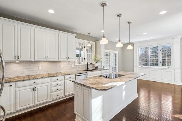 kitchen with white cabinetry, black electric stovetop, decorative light fixtures, a kitchen island, and light stone counters