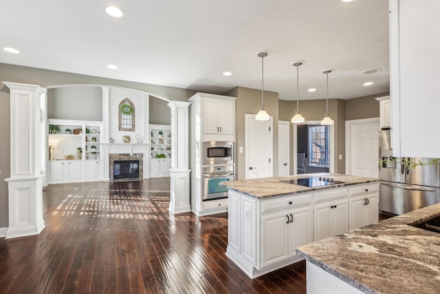 kitchen featuring ornate columns, a kitchen island, white cabinetry, and stainless steel appliances