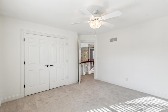 unfurnished bedroom with ceiling fan, a closet, and light carpet