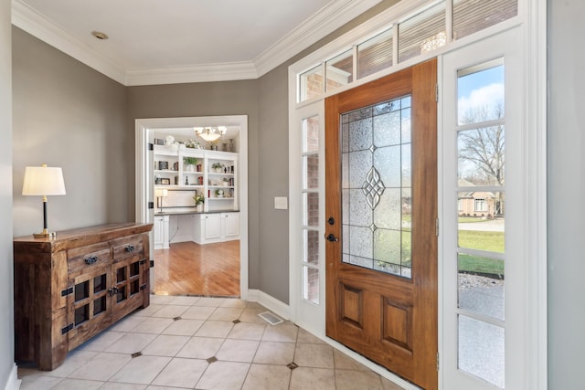 tiled entrance foyer featuring an inviting chandelier and ornamental molding