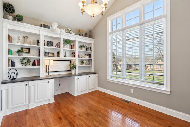 unfurnished office with a wealth of natural light, built in desk, and a chandelier