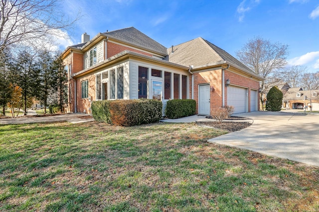 front facade featuring a sunroom, a garage, and a front yard