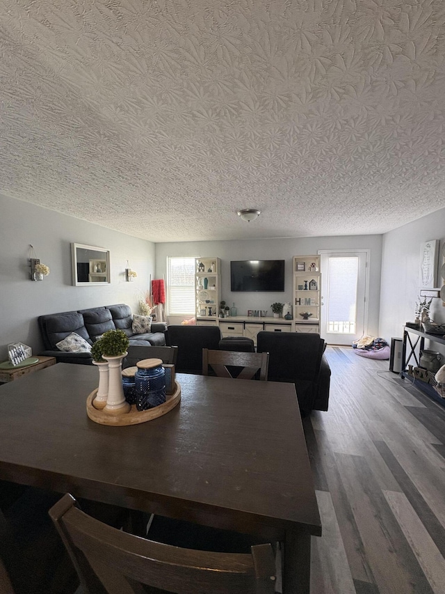 dining area with wood-type flooring and a textured ceiling