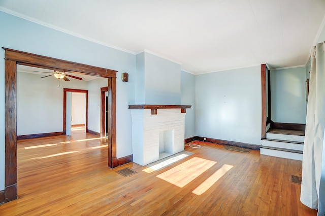 unfurnished living room featuring hardwood / wood-style flooring, a fireplace, ornamental molding, and ceiling fan