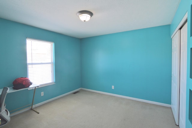 unfurnished bedroom featuring light colored carpet and a closet