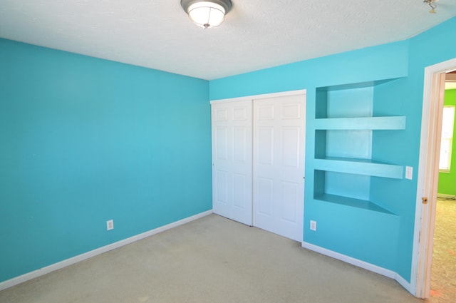 unfurnished bedroom with a textured ceiling, a closet, and light carpet