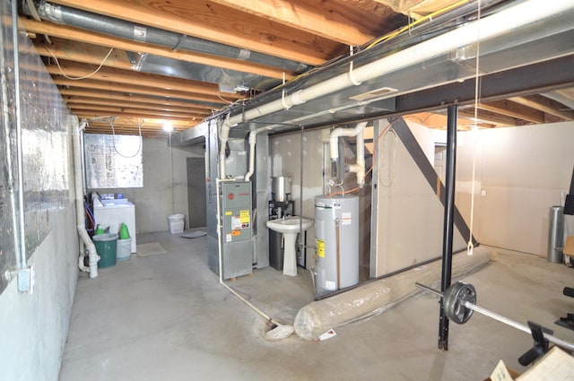 basement featuring water heater, washer / dryer, and heating unit