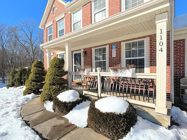 snow covered property entrance with covered porch