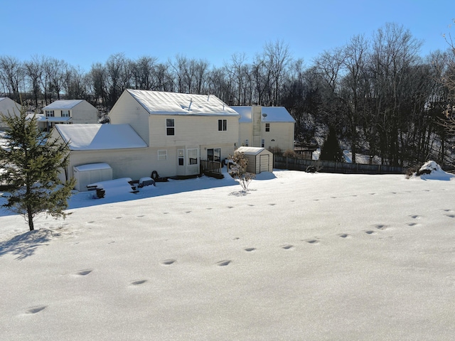 snow covered back of property featuring a storage unit