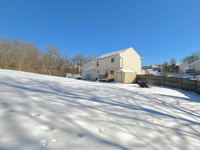 snow covered house featuring a storage unit